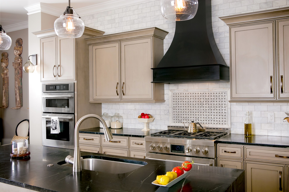 Foto di una cucina classica con lavello sottopiano, ante a filo, ante beige, paraspruzzi grigio e elettrodomestici in acciaio inossidabile