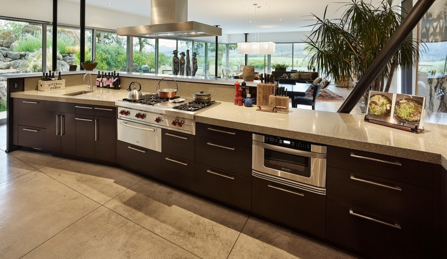 Kitchen - mid-sized tropical u-shaped concrete floor and gray floor kitchen idea in Vancouver with a single-bowl sink, flat-panel cabinets, dark wood cabinets, limestone countertops, window backsplash, stainless steel appliances and a peninsula
