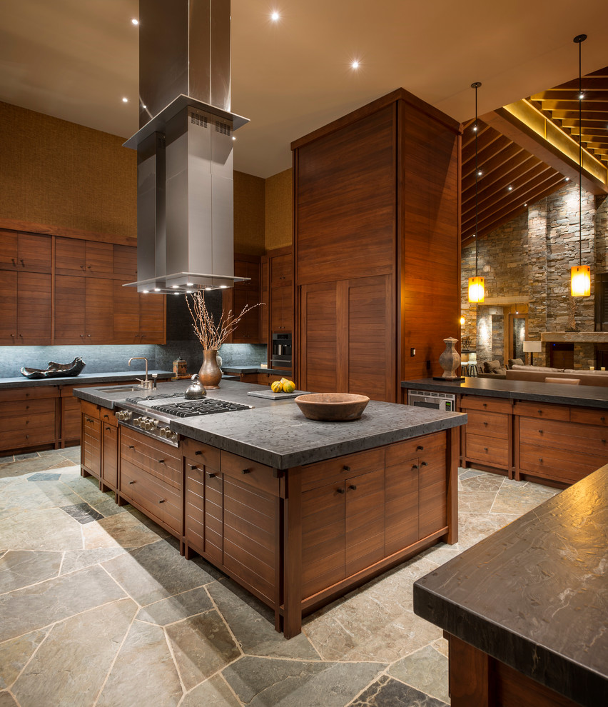 Cette image montre une cuisine ouverte chalet en U et bois brun avec un placard à porte plane, une crédence grise et une crédence en ardoise.
