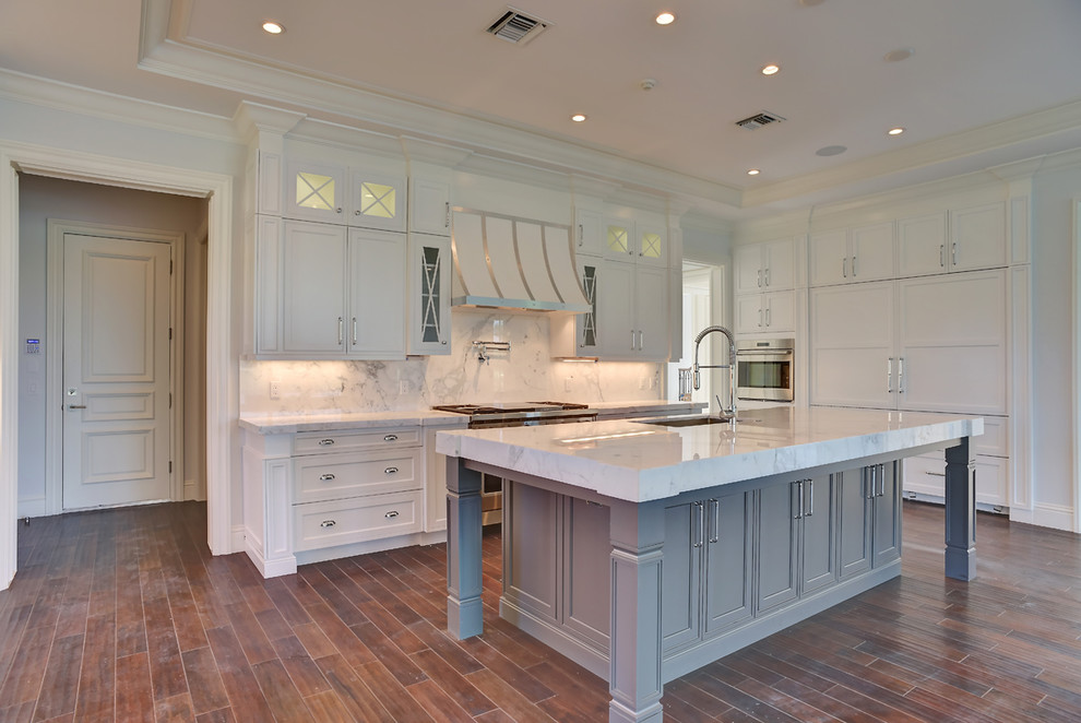Inspiration för ett stort vintage kök, med en undermonterad diskho, luckor med infälld panel, vita skåp, marmorbänkskiva, vitt stänkskydd, stänkskydd i marmor, integrerade vitvaror, mörkt trägolv, en köksö och brunt golv