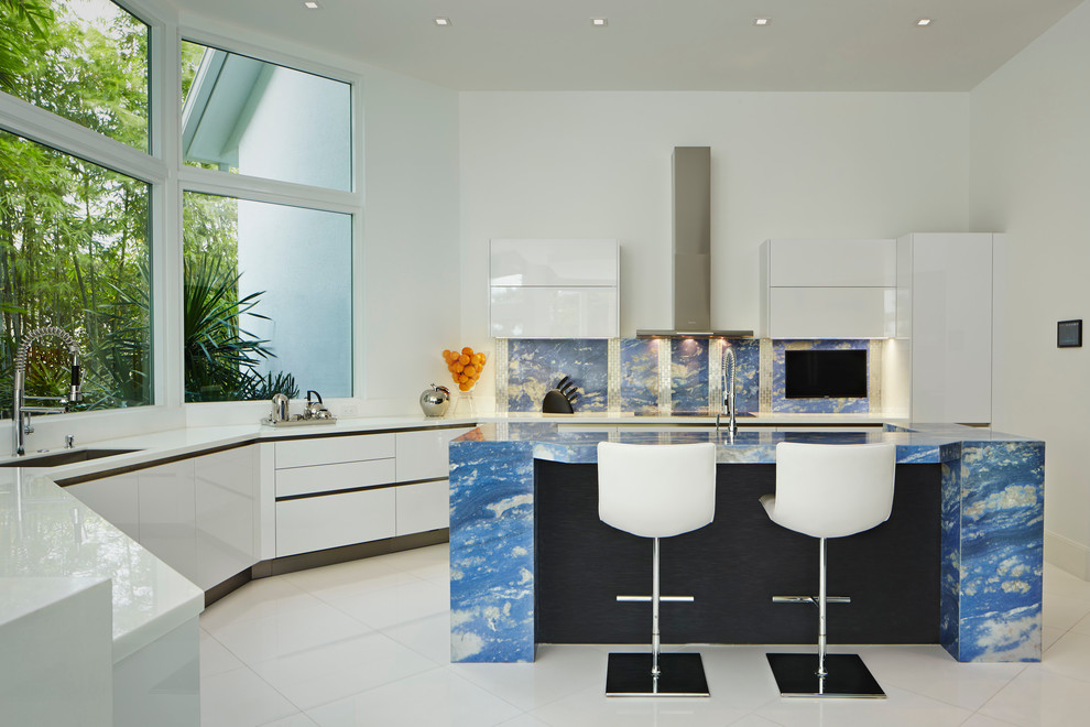Cette photo montre une cuisine tendance en U avec un placard à porte plane, des portes de placard blanches, une crédence bleue, îlot et un plan de travail bleu.
