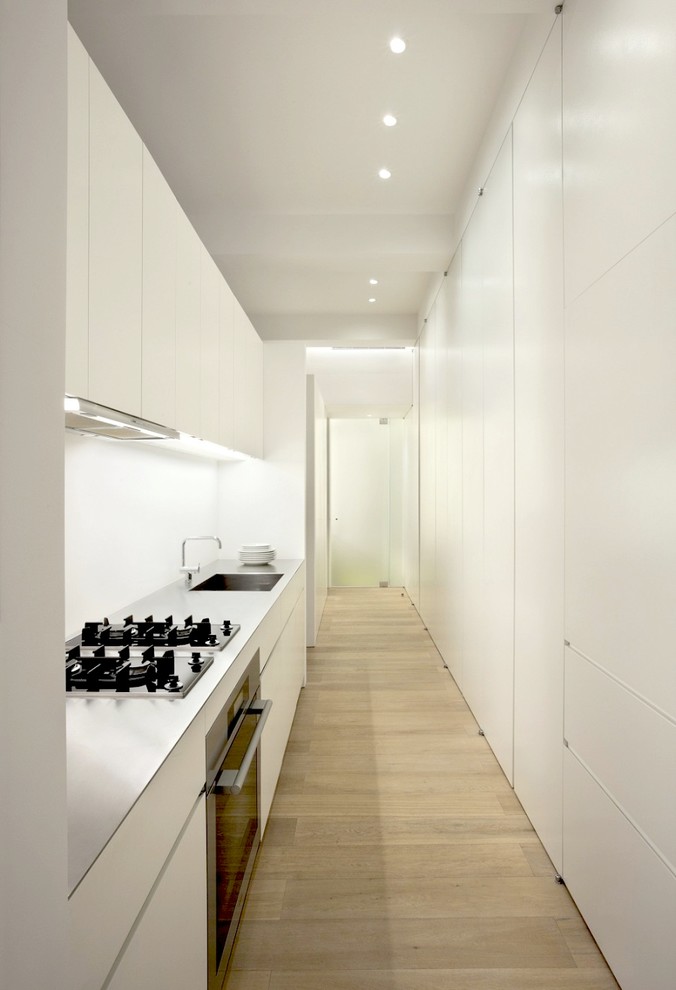 Idées déco pour une petite cuisine linéaire moderne fermée avec un sol en bois brun et un électroménager blanc.
