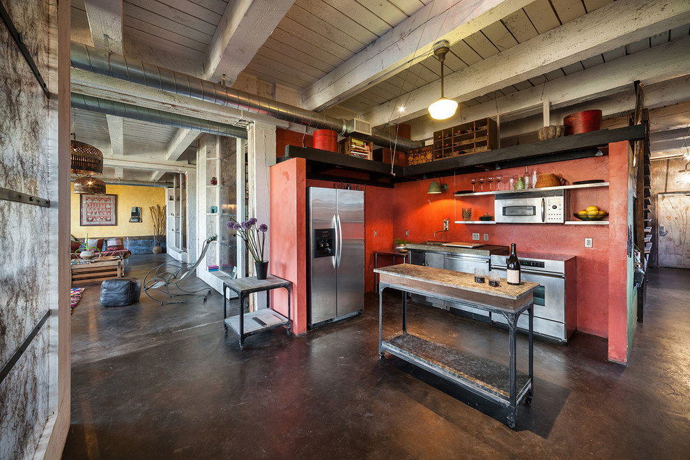 Industrial Küche in L-Form mit Küchengeräten aus Edelstahl, Kücheninsel, Edelstahlfronten, Betonboden, Unterbauwaschbecken und Küchenrückwand in Rot in Portland