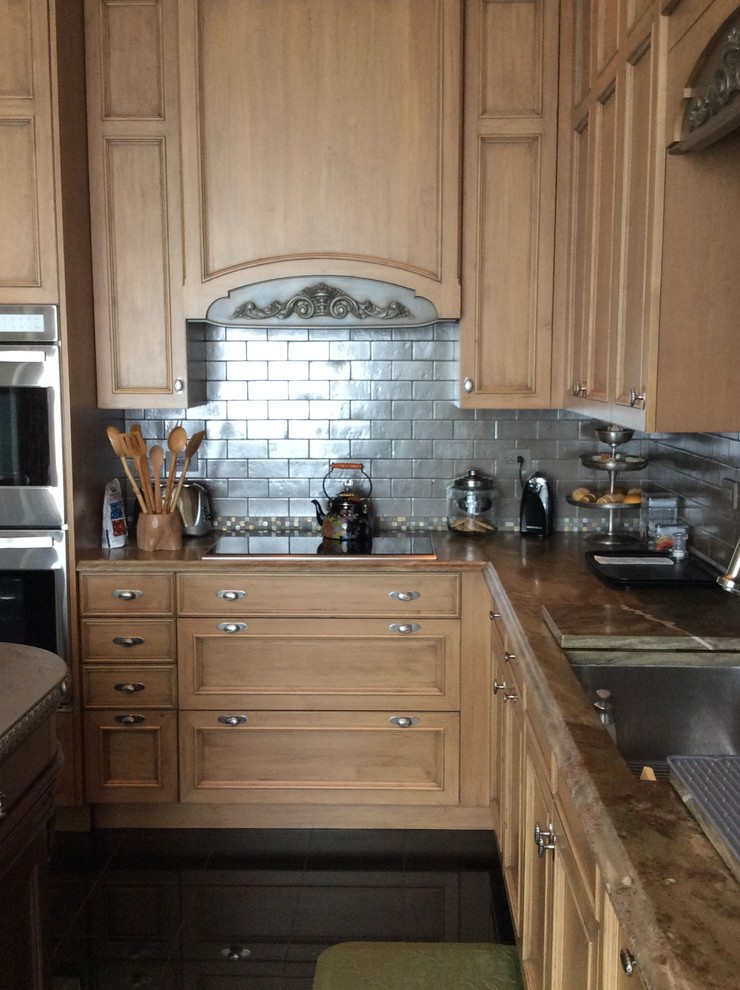 This is an example of a medium sized bohemian u-shaped enclosed kitchen in Chicago with a belfast sink, raised-panel cabinets, light wood cabinets, quartz worktops, metallic splashback, metro tiled splashback, integrated appliances, marble flooring and an island.