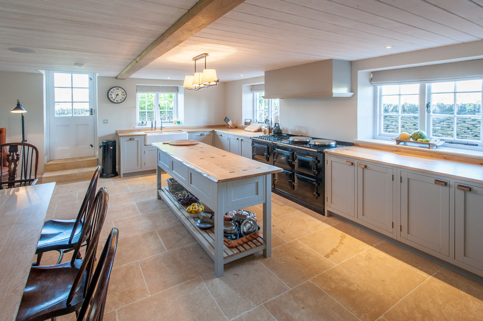 Photo of a large classic l-shaped kitchen/diner in Gloucestershire with a belfast sink, recessed-panel cabinets, grey cabinets, wood worktops, integrated appliances, porcelain flooring and an island.