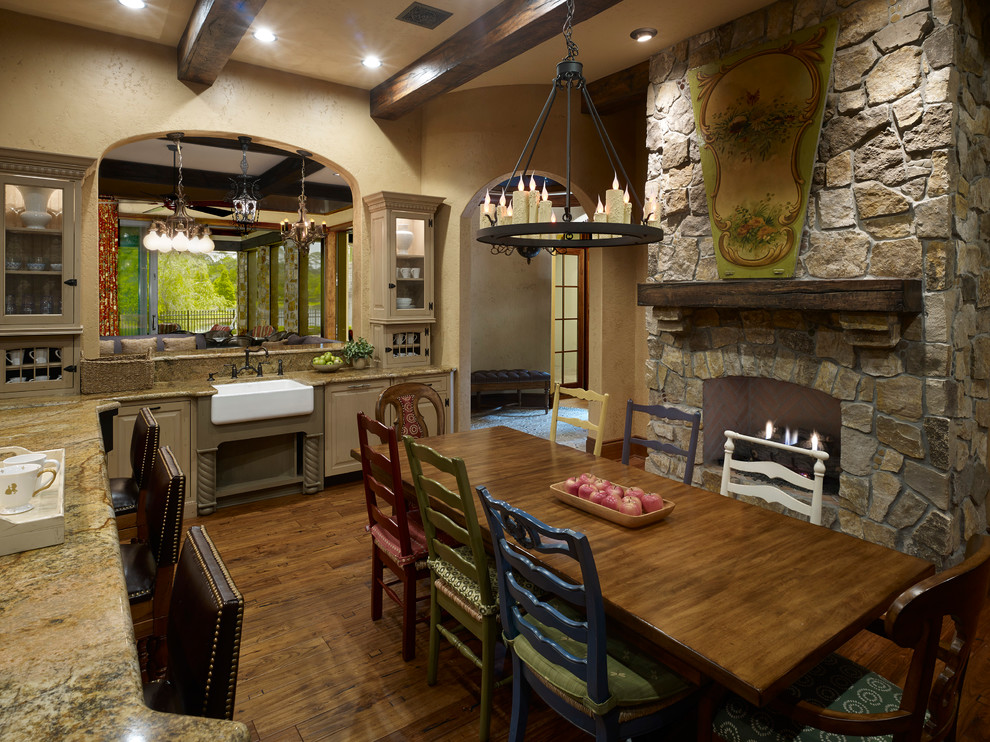 Exempel på ett medelhavsstil kök, med luckor med upphöjd panel, skåp i mörkt trä, granitbänkskiva, integrerade vitvaror, mellanmörkt trägolv och en köksö