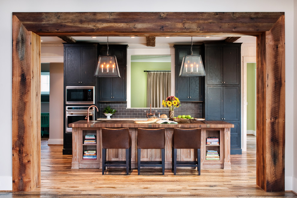 Immagine di una cucina parallela rustica con ante in stile shaker, ante nere, top in legno, paraspruzzi grigio, paraspruzzi con piastrelle diamantate e elettrodomestici in acciaio inossidabile