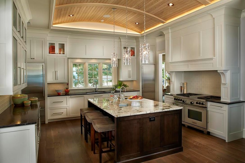 Modern inredning av ett stort kök, med en undermonterad diskho, luckor med infälld panel, vita skåp, granitbänkskiva, beige stänkskydd, stänkskydd i glaskakel, rostfria vitvaror, mellanmörkt trägolv, en köksö och brunt golv