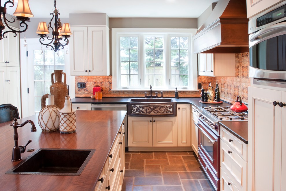 Idéer för ett klassiskt kök, med en rustik diskho, luckor med upphöjd panel, vita skåp, orange stänkskydd, stänkskydd i keramik, rostfria vitvaror, klinkergolv i porslin och en köksö