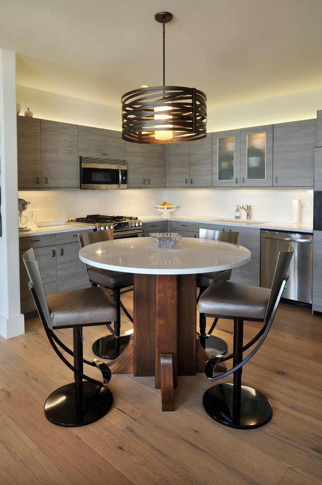 Exempel på ett modernt kök, med en undermonterad diskho, släta luckor, grå skåp, vitt stänkskydd, rostfria vitvaror och mellanmörkt trägolv