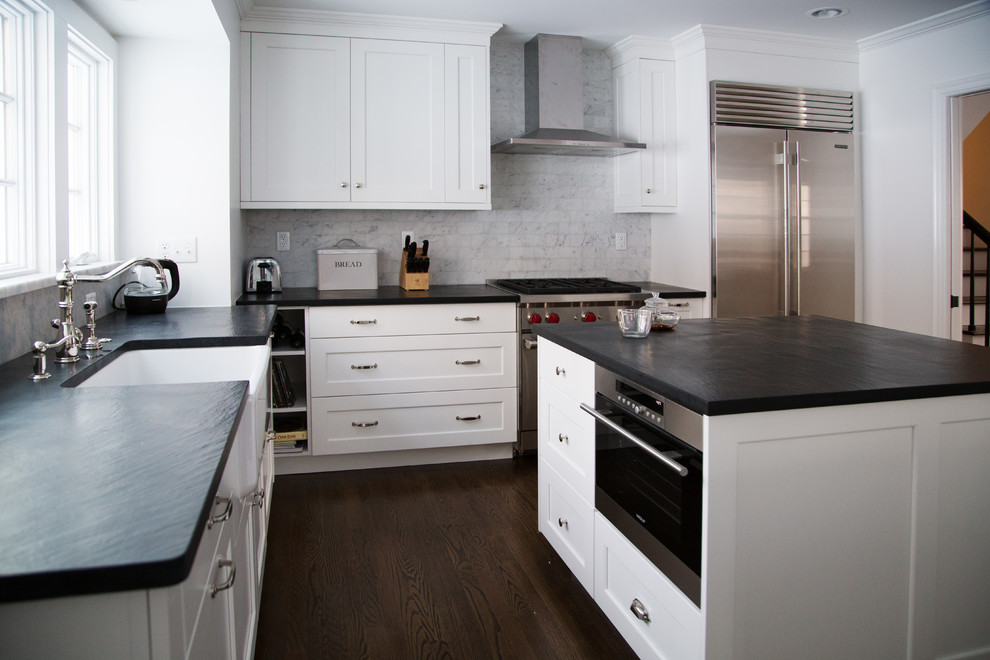 Modern inredning av ett stort kök, med en rustik diskho, luckor med infälld panel, vita skåp, grått stänkskydd, stänkskydd i tunnelbanekakel, rostfria vitvaror, mörkt trägolv och flera köksöar