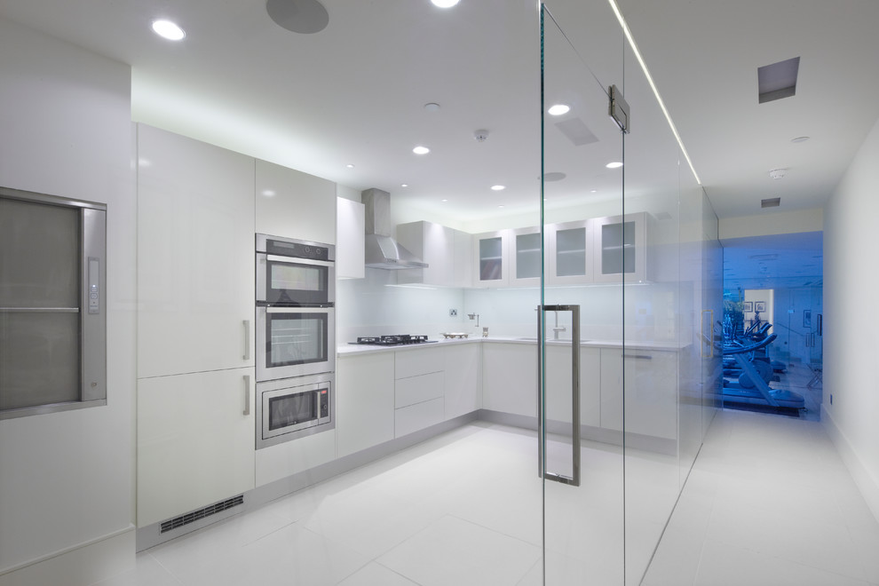 Photo of a medium sized contemporary kitchen in London with a submerged sink, flat-panel cabinets, white cabinets, composite countertops, white splashback, glass sheet splashback, stainless steel appliances and porcelain flooring.
