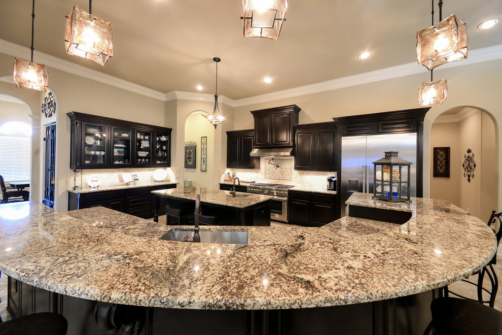 Example of a mid-sized tuscan l-shaped porcelain tile open concept kitchen design in Houston with a farmhouse sink, dark wood cabinets, quartzite countertops, stainless steel appliances, an island, glass-front cabinets, white backsplash and ceramic backsplash
