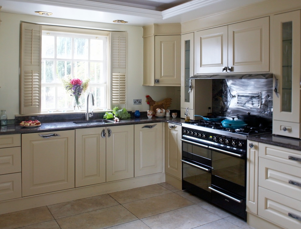 Immagine di una cucina chic di medie dimensioni con lavello da incasso, ante con bugna sagomata, ante beige, top in granito, paraspruzzi con piastrelle di metallo e pavimento in gres porcellanato