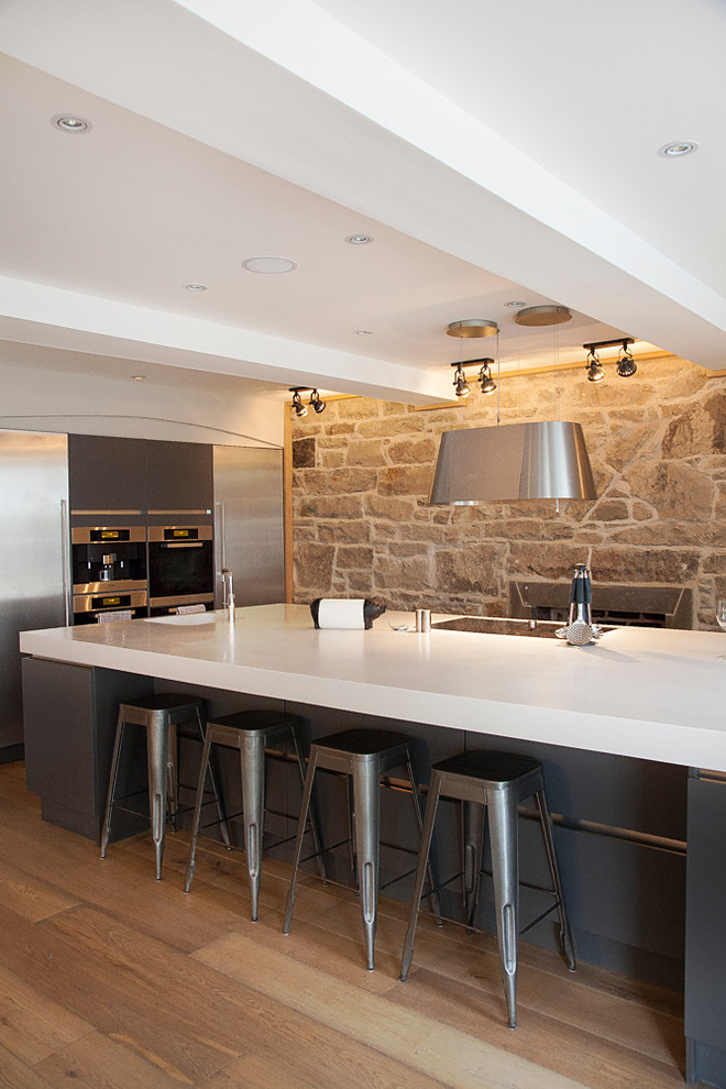 Medium sized farmhouse kitchen in Other with stainless steel appliances, medium hardwood flooring, an island, brown floors, white worktops, flat-panel cabinets, blue cabinets and limestone worktops.