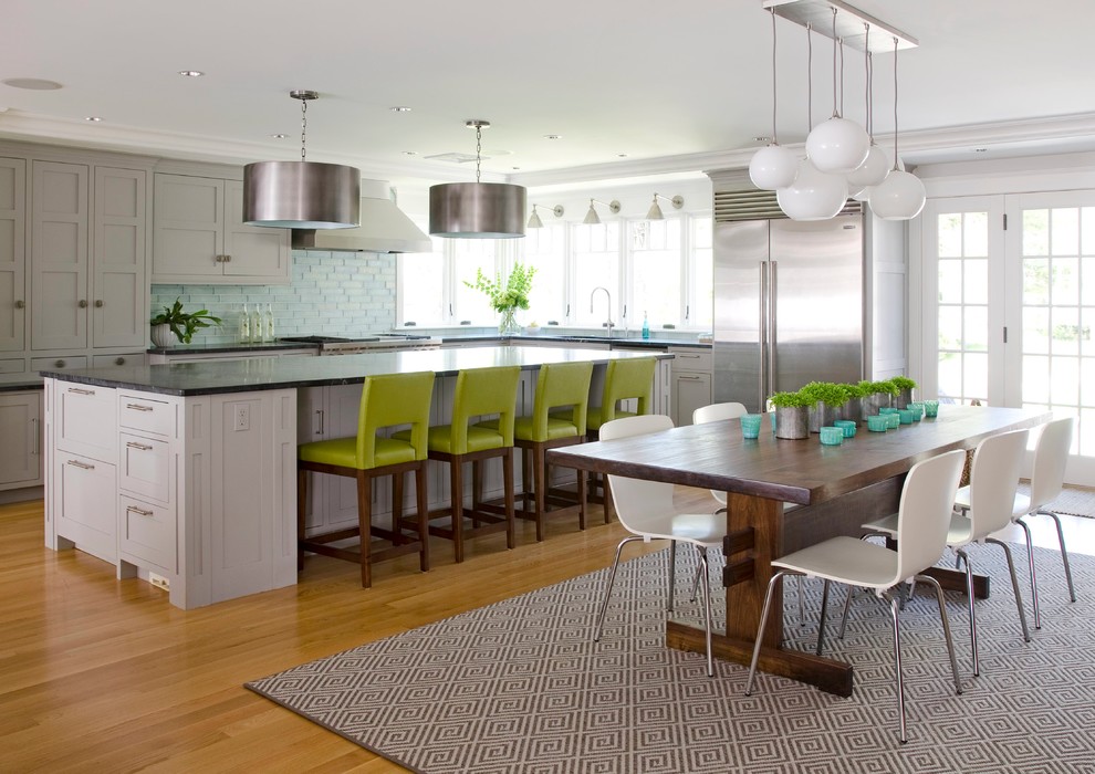 Bild på ett funkis kök, med skåp i shakerstil, grå skåp, blått stänkskydd, rostfria vitvaror, mellanmörkt trägolv, en köksö och brunt golv