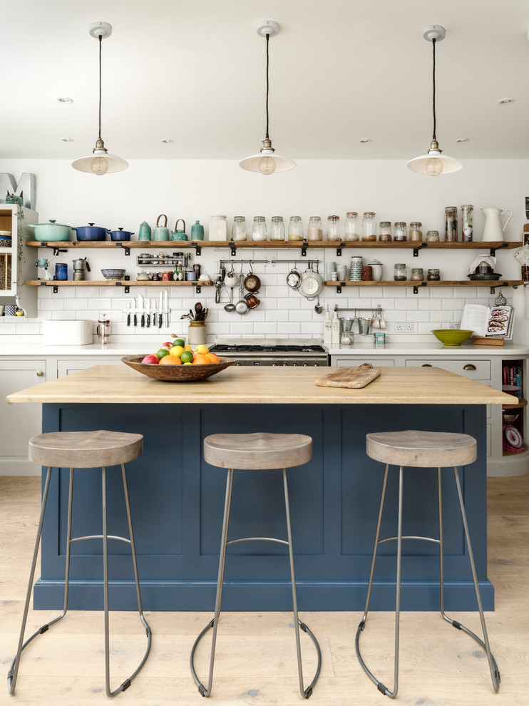 Large trendy light wood floor eat-in kitchen photo in London with raised-panel cabinets, solid surface countertops, an island and white countertops