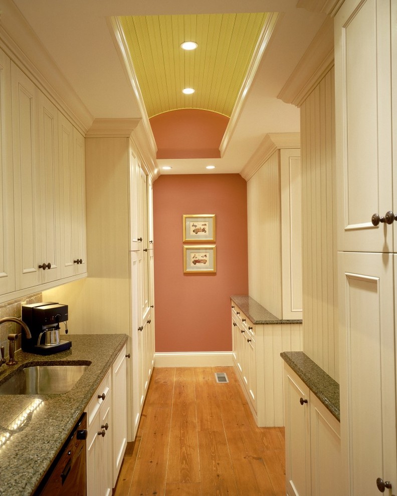 Cette photo montre une cuisine parallèle chic avec un évier encastré, un placard avec porte à panneau encastré, des portes de placard blanches et une crédence beige.