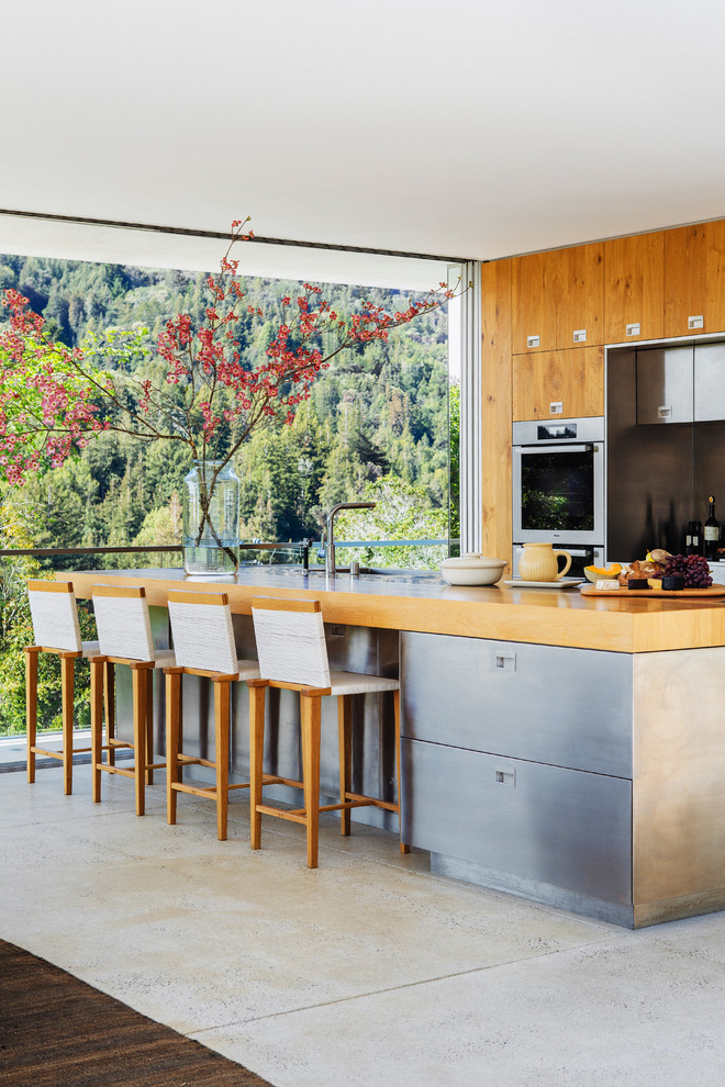 Foto de cocina actual con una isla, fregadero bajoencimera, armarios con paneles lisos, puertas de armario de madera oscura, electrodomésticos de acero inoxidable y suelo de madera oscura