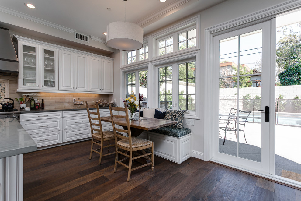 Foto de cocina lineal clásica grande abierta con puertas de armario blancas, electrodomésticos de acero inoxidable, suelo de madera en tonos medios y una isla