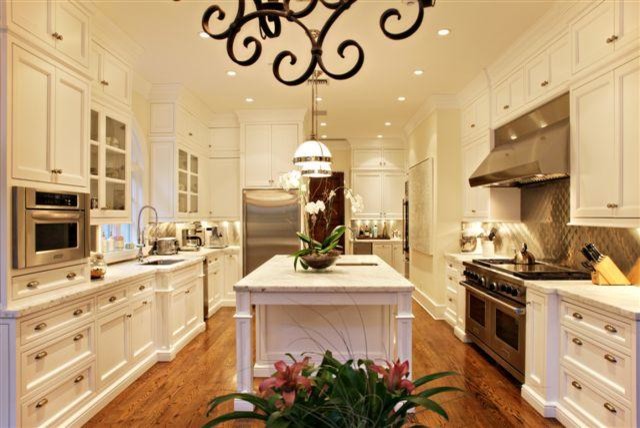 Exempel på ett klassiskt kök, med en undermonterad diskho, luckor med profilerade fronter, vita skåp, marmorbänkskiva, stänkskydd med metallisk yta, stänkskydd i metallkakel och rostfria vitvaror