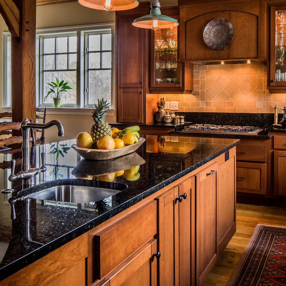 Foto på ett mellanstort amerikanskt kök, med en undermonterad diskho, luckor med infälld panel, skåp i mellenmörkt trä, granitbänkskiva, svart stänkskydd, stänkskydd i sten, rostfria vitvaror, mellanmörkt trägolv och en köksö