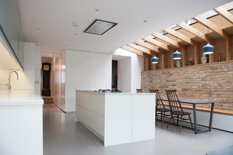 На фото: параллельная кухня в современном стиле с обеденным столом, плоскими фасадами, белыми фасадами, бетонным полом и островом