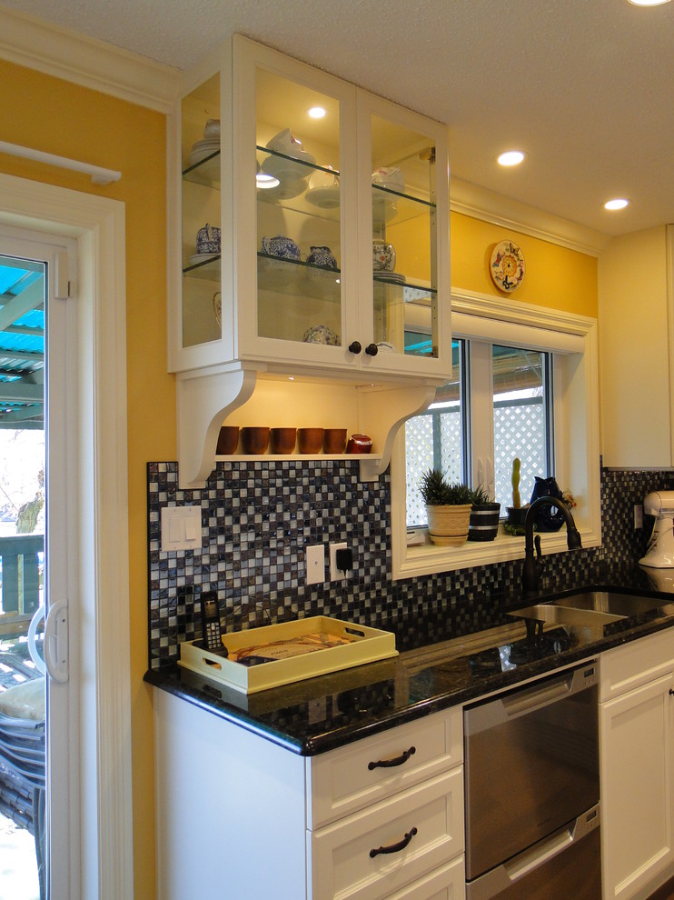 Klassisk inredning av ett mellanstort kök, med en undermonterad diskho, luckor med infälld panel, vita skåp, granitbänkskiva, flerfärgad stänkskydd, stänkskydd i mosaik, rostfria vitvaror och mellanmörkt trägolv