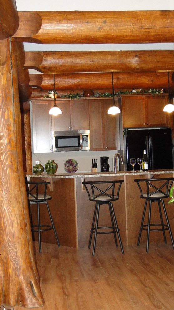 Exemple d'une cuisine ouverte parallèle montagne en bois brun de taille moyenne avec un évier 2 bacs, un placard à porte shaker, un plan de travail en stratifié, un électroménager noir, parquet clair et îlot.