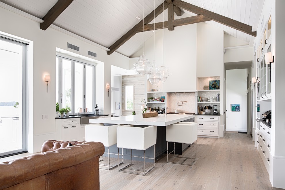 Modern inredning av ett stort kök, med luckor med glaspanel, vita skåp, vitt stänkskydd, stänkskydd i mosaik, ljust trägolv och en köksö