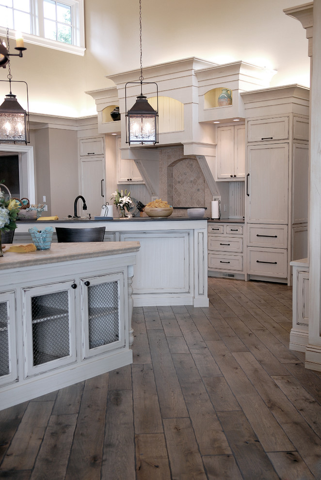 Inspiration for a huge coastal u-shaped medium tone wood floor, brown floor and vaulted ceiling eat-in kitchen remodel in Chicago with an undermount sink, beaded inset cabinets, white cabinets, granite countertops, multicolored backsplash, ceramic backsplash, two islands and black countertops