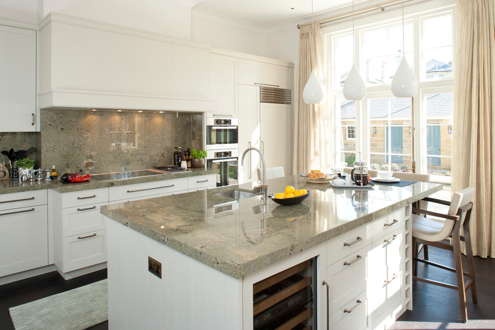 Ejemplo de cocina contemporánea con armarios estilo shaker, puertas de armario blancas, salpicadero verde y electrodomésticos con paneles