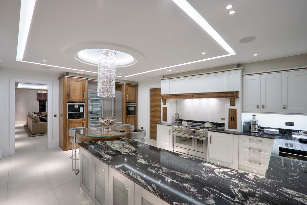 Moderne Wohnküche in U-Form mit integriertem Waschbecken, Schrankfronten im Shaker-Stil, weißen Schränken und Küchengeräten aus Edelstahl in London