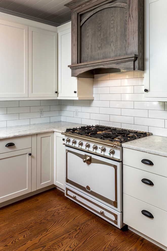 Mid-sized farmhouse l-shaped medium tone wood floor eat-in kitchen photo in Portland Maine with an undermount sink, shaker cabinets, gray cabinets, marble countertops, white backsplash, subway tile backsplash, stainless steel appliances and an island