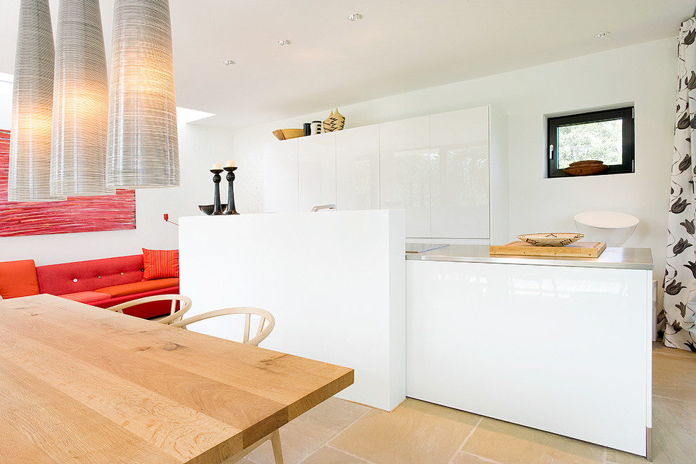 Immagine di una cucina minimalista di medie dimensioni con ante lisce, ante bianche, top in acciaio inossidabile e pavimento in travertino