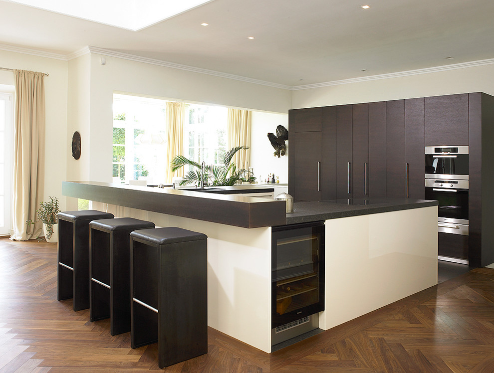 Foto di una cucina design con ante lisce, ante marroni, elettrodomestici neri e pavimento in legno massello medio