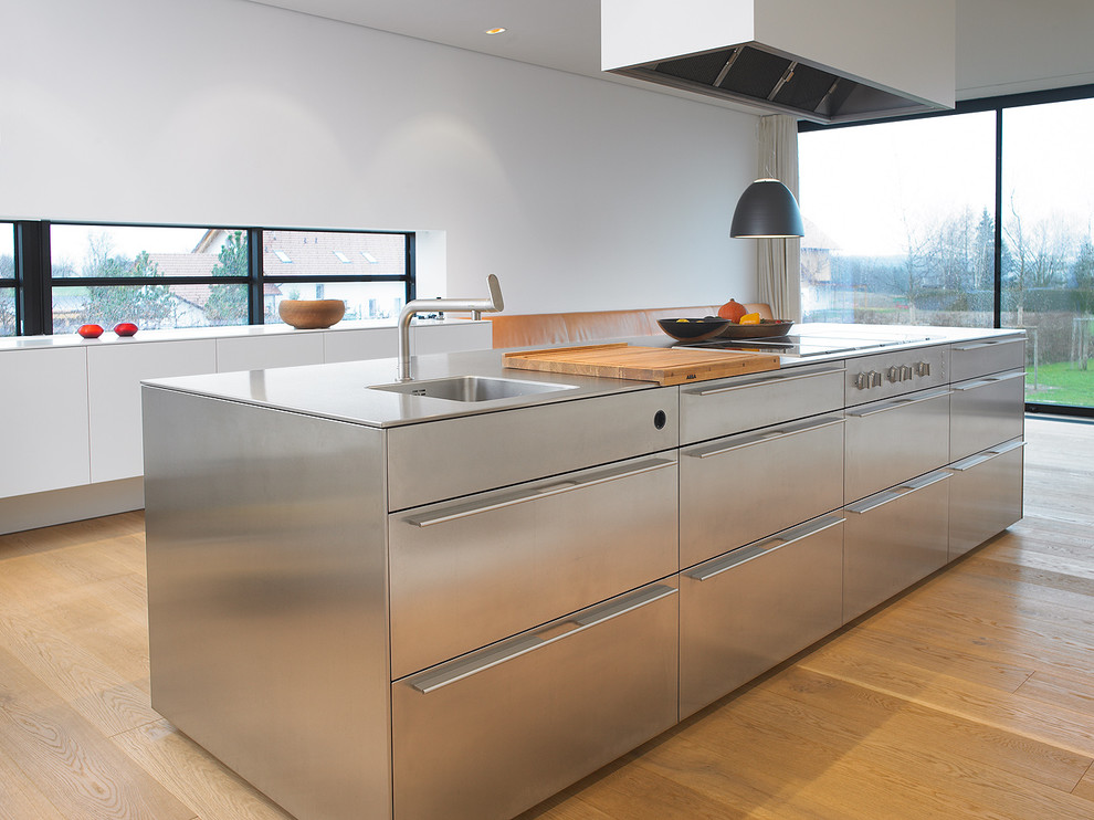 Ejemplo de cocina minimalista con fregadero integrado y puertas de armario en acero inoxidable