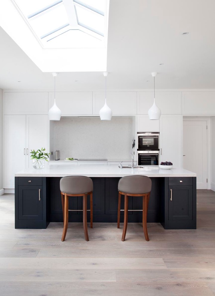 Inspiration for a contemporary kitchen in Dublin with shaker cabinets, quartz worktops, stainless steel appliances, light hardwood flooring, an island and white splashback.