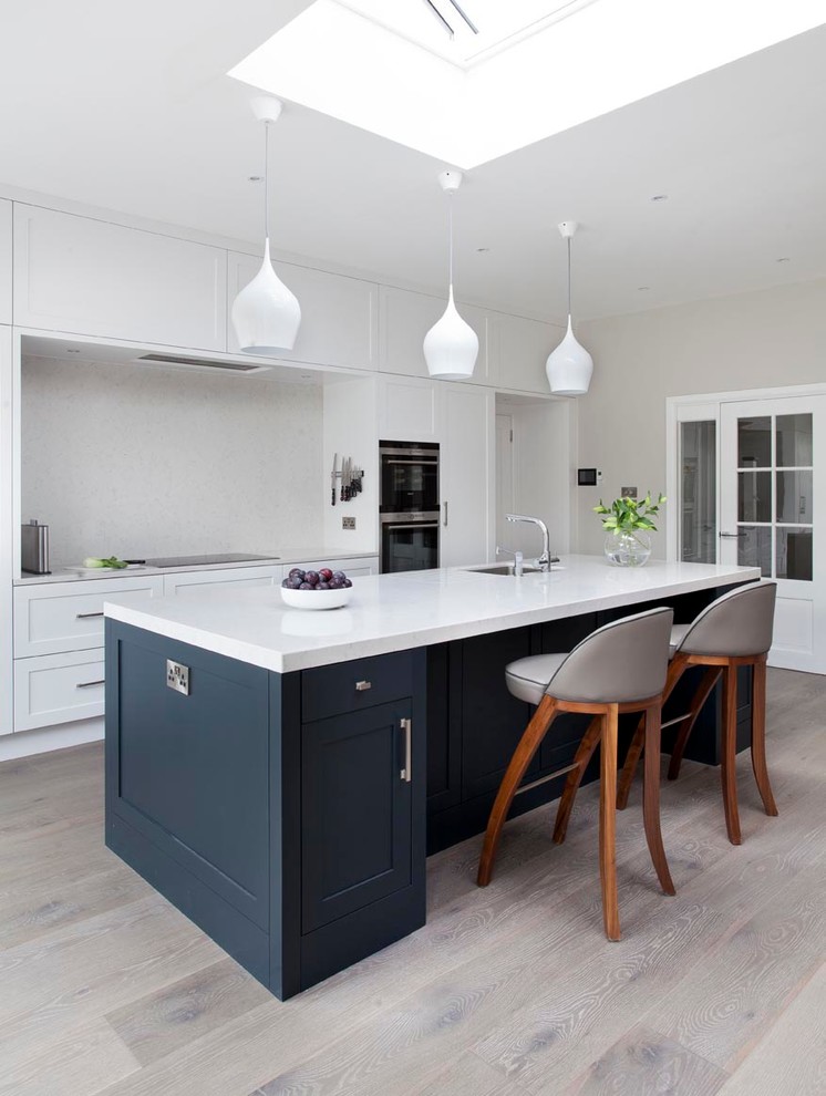 Design ideas for a medium sized modern single-wall kitchen/diner in Dublin with shaker cabinets, quartz worktops, black appliances, medium hardwood flooring and an island.