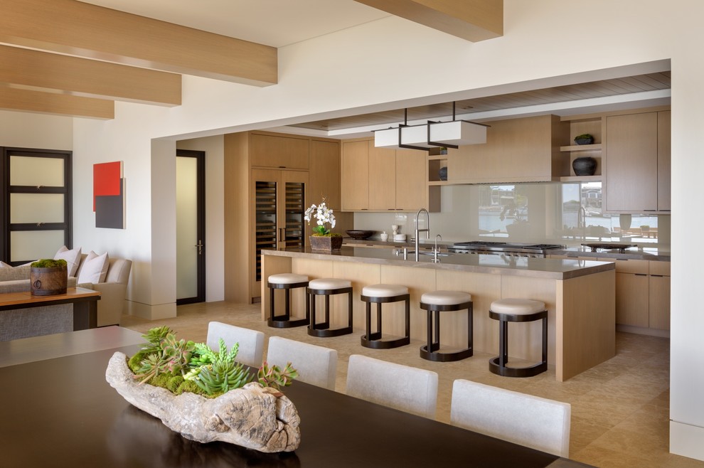 Cette image montre une grande cuisine ouverte design en bois clair avec un placard à porte plane, une crédence beige, une crédence en feuille de verre, un électroménager en acier inoxydable et îlot.