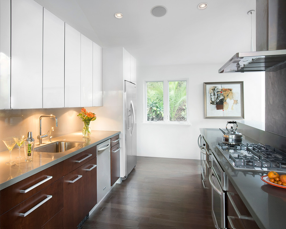 Inspiration for a transitional galley kitchen remodel in Santa Barbara with an undermount sink, flat-panel cabinets, medium tone wood cabinets, beige backsplash, glass sheet backsplash and stainless steel appliances