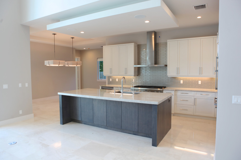 Example of a large trendy single-wall ceramic tile, white floor and coffered ceiling open concept kitchen design in Miami with a farmhouse sink, flat-panel cabinets, white cabinets, granite countertops, gray backsplash, ceramic backsplash, stainless steel appliances, an island and white countertops