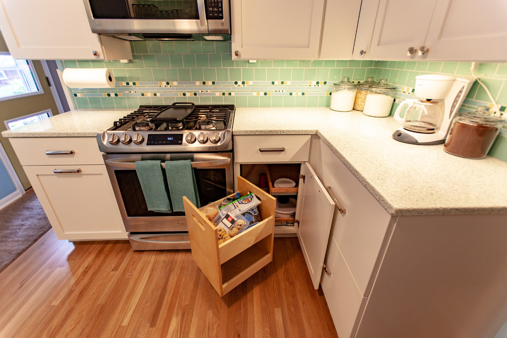 This is an example of a midcentury enclosed kitchen in Minneapolis with a submerged sink, shaker cabinets, white cabinets, recycled glass countertops, green splashback, mosaic tiled splashback, stainless steel appliances, medium hardwood flooring, no island, brown floors and white worktops.