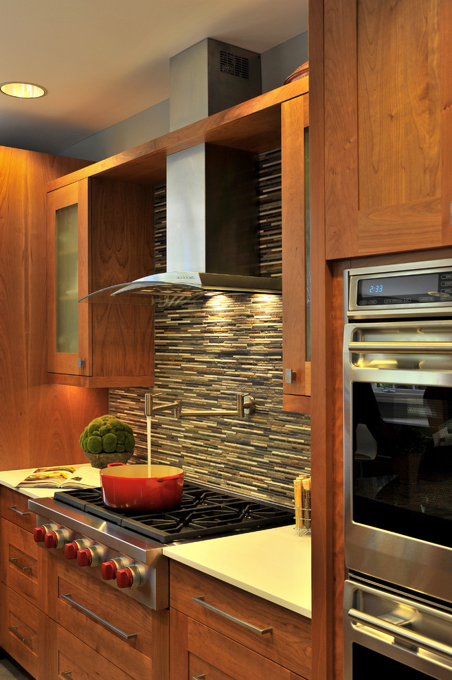 Bild på ett stort funkis kök, med en undermonterad diskho, skåp i shakerstil, skåp i mellenmörkt trä, granitbänkskiva, flerfärgad stänkskydd, stänkskydd i stickkakel, integrerade vitvaror, klinkergolv i keramik och en köksö