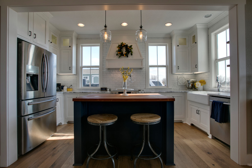 Foto på ett stort lantligt kök, med en rustik diskho, skåp i shakerstil, vita skåp, marmorbänkskiva, vitt stänkskydd, stänkskydd i tunnelbanekakel, rostfria vitvaror, mellanmörkt trägolv, en köksö och brunt golv