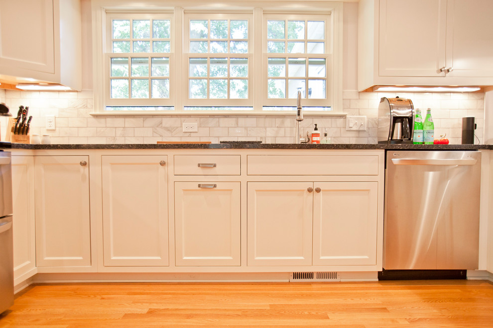 Inspiration för eklektiska svart kök med öppen planlösning, med en undermonterad diskho, luckor med infälld panel, vita skåp, beige stänkskydd, stänkskydd i marmor, rostfria vitvaror, mellanmörkt trägolv, en halv köksö och brunt golv