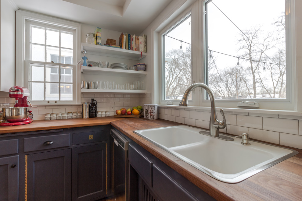 Photo of a large scandi l-shaped open plan kitchen in Minneapolis with a double-bowl sink, recessed-panel cabinets, blue cabinets, wood worktops, white splashback, metro tiled splashback, stainless steel appliances, medium hardwood flooring, a breakfast bar and brown floors.