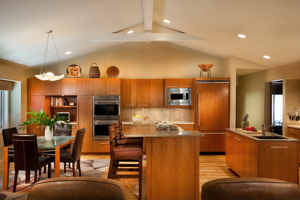Moderne Wohnküche mit Unterbauwaschbecken, flächenbündigen Schrankfronten, hellbraunen Holzschränken, Küchenrückwand in Beige und Küchengeräten aus Edelstahl in Omaha