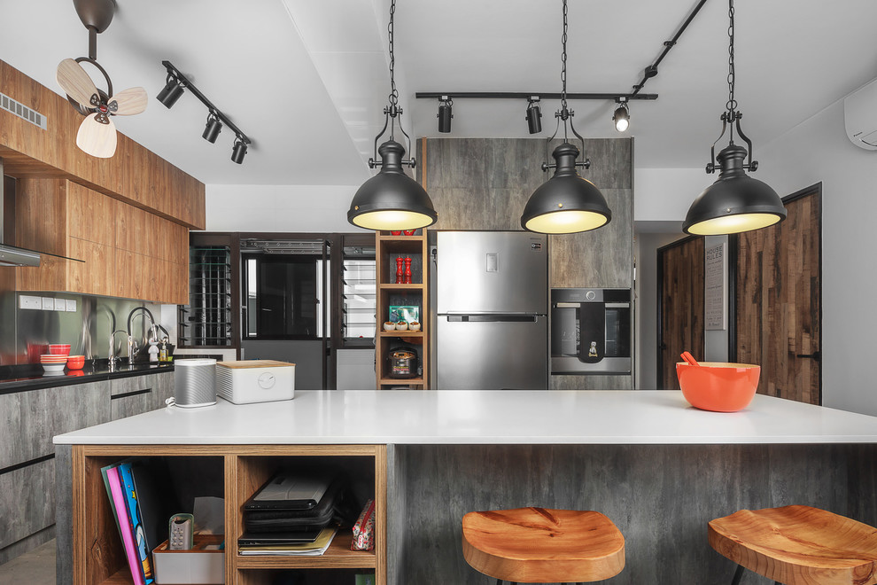 Industrial l-shaped kitchen in Singapore with a submerged sink, flat-panel cabinets, medium wood cabinets, metallic splashback, metal splashback, stainless steel appliances, an island and white worktops.