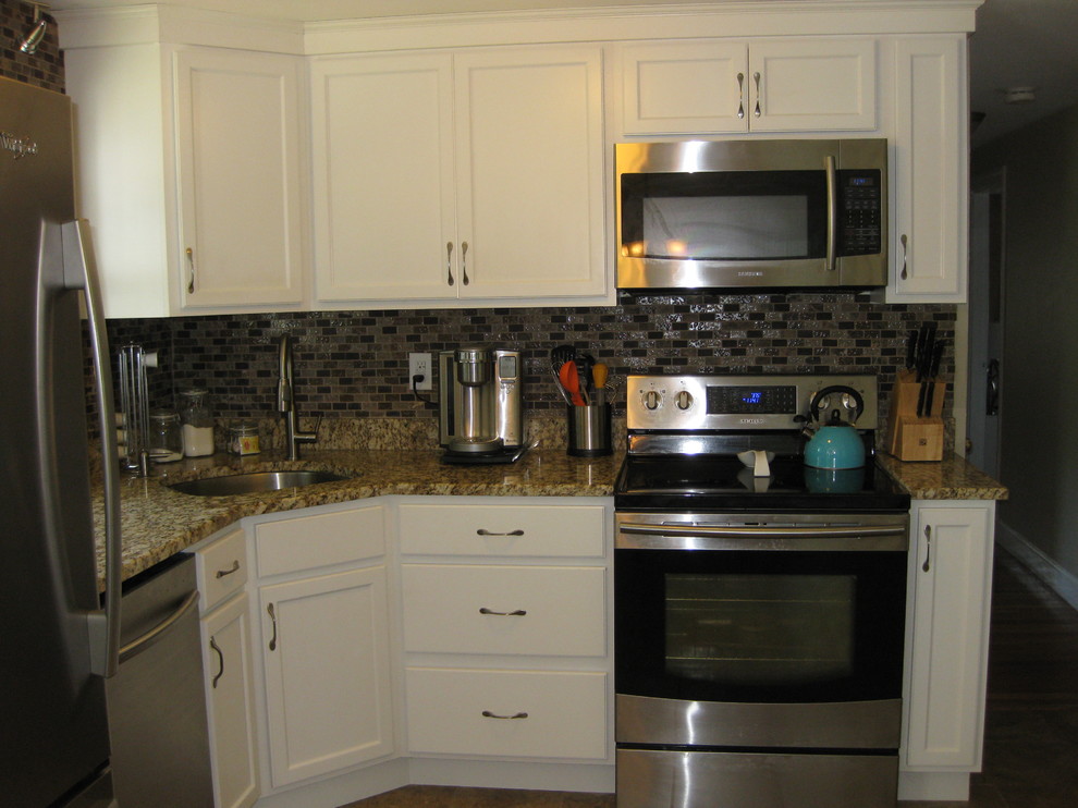 Exempel på ett litet klassiskt beige beige l-kök, med en undermonterad diskho, luckor med infälld panel, vita skåp, granitbänkskiva, brunt stänkskydd, rostfria vitvaror, stänkskydd i glaskakel, klinkergolv i porslin och brunt golv